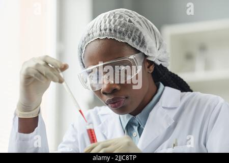 Portrait of young black woman wearing protective glasses while working in medical laboratory Stock Photo