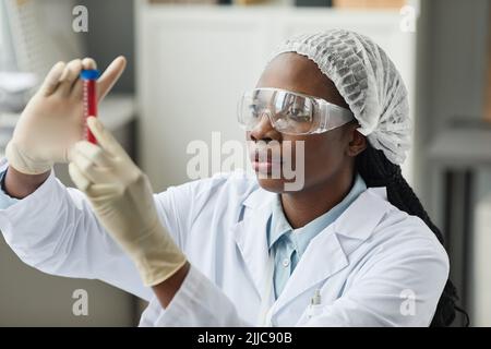 Portrait of young black woman holding test tube while working in science laboratory Stock Photo