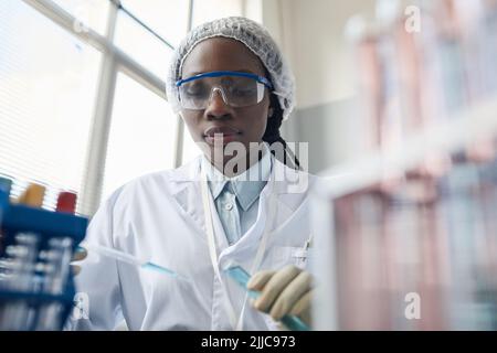 Portrait of black female scientist wearing protective glasses while doing experiments in lab Stock Photo