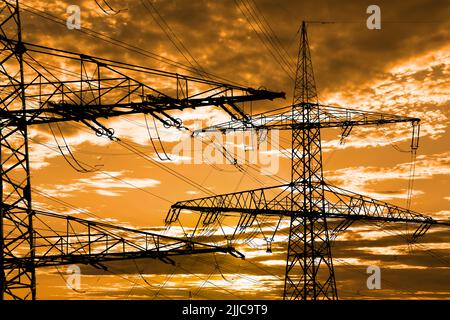 Many elecrtic poles in front of sky with clouds Stock Photo