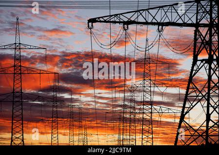 Many elecrtic poles in front of sky with clouds Stock Photo