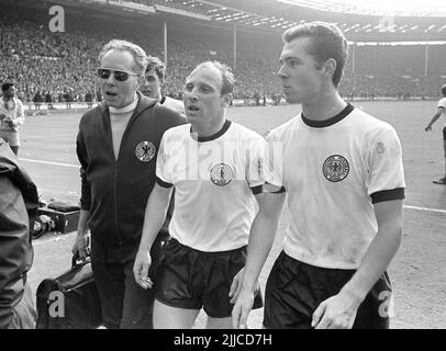 ARCHIVE PHOTO: UWE SEELER DIED AT THE AGE OF 85. Final of the football World Cup 1966 in London's Wembley Stadium England - Federal Republic of Germany 4:3, masseur Erich DEUSER, the players Uwe SEELER and Franz BECKENBAUER (from left) leave the field, horizontal format, B&W photo, July 30th, 1966. © Stock Photo