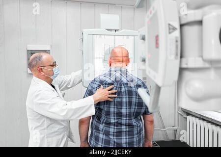 Doctor correctly positioning a patient in front of an x-ray machine Stock Photo