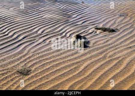 Patterns and ripples left by the water on the beach next to some rocks, Kiyu, San Jose, Uruguay Stock Photo