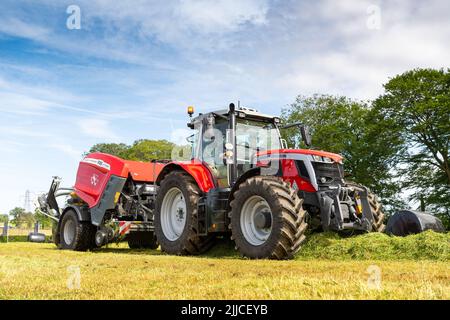 Big baling grass on a meadow using a Massey Ferguson tractor and a 3130DF baler and wrapper. Dumfries, Scotland. Stock Photo
