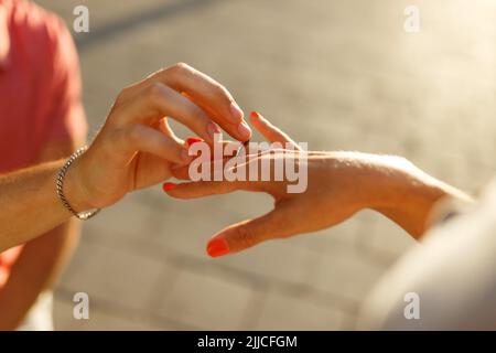 Young man with engagement ring making proposal to his beloved girlfriend outdoors.  Stock Photo