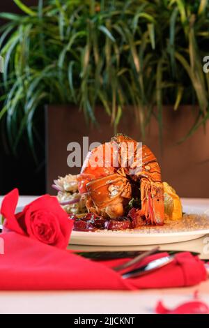 An appetizing cooked lobster tail with lemon served on a white plate Stock Photo