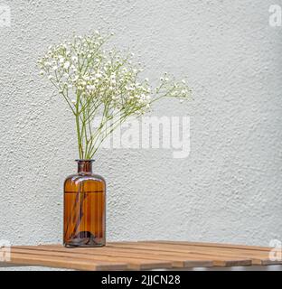 Still Life with minimal floral composition on wooden table at a street cafe Stock Photo