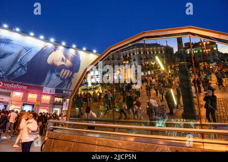 Crowds in The Puerta del Sol, at night with the famous Tio Pepe advertising sign reflected in the windows of the Sol Metro station.  Madrid, Spain. Stock Photo