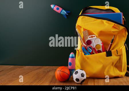 School backpack with colorful school supplies on table. Stock Photo