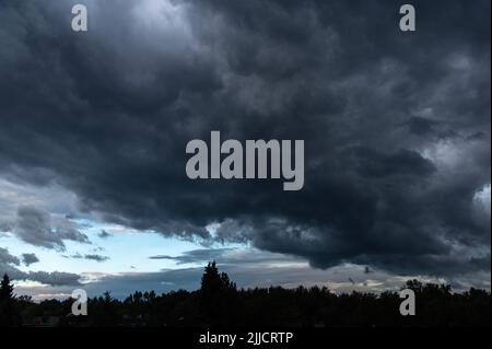 Stormy sky with dramatic dark clouds with the line of trees in the sunset time Stock Photo
