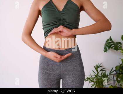 Cropped shot of a young multi-ethnic woman's stomach cupped by her hands Stock Photo
