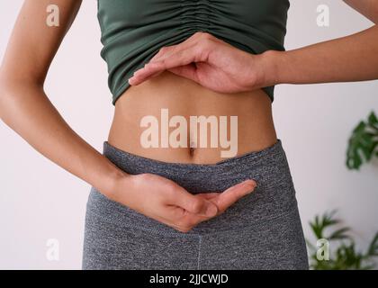 Close up of a young multi-ethnic woman's stomach cupped by her hands Stock Photo