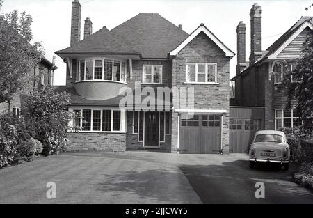 1970s, historical, exterior, front view of a newly built, large, brick-built detached suburban house, England, UK. A 1960s motorcar, a Wolseley 1500 is parked on the driveway, Stock Photo