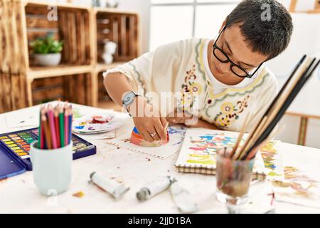 Young hispanic woman painting clay ceramic at art studio Stock Photo