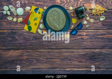 Vacation accessories on the dark brown wooden boards. Location: centered at the bottom. Travel hat, camera, document holder with passport, sunglasses. Stock Photo