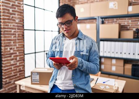 Down syndrome man ecommerce business worker using touchpad at office Stock Photo