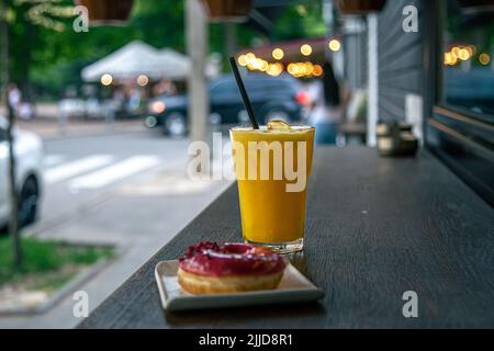 Close-up, juice and donut on a blurred background of the city. Stock Photo