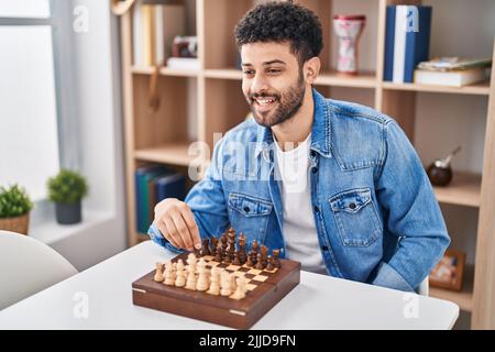 Young arab man playing chess sitting on table at home Stock Photo