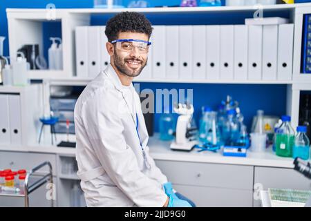 Young arab man wearing scientist uniform smiling confident at laboratory Stock Photo