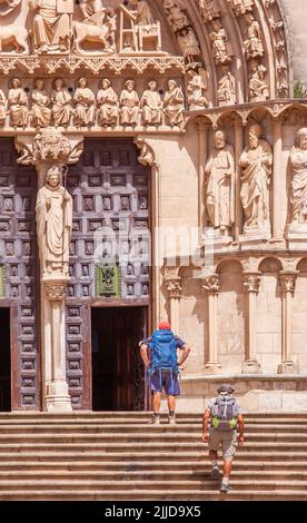 Two pilgrims walking the Camino de Santiago on the steps to the cathedral of St Mary the virgin in the Spanish city of Burgos Spain Stock Photo