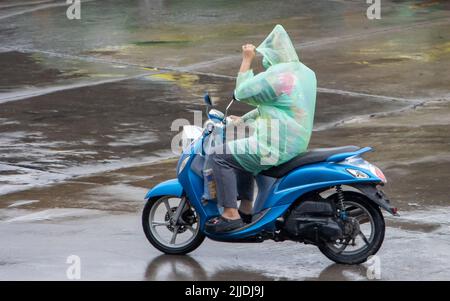 A man with a raincoat rides a motorcycle in the rain Stock Photo