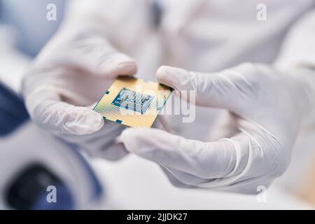 African american woman wearing scientist uniform holding cpu microchip at laboratory Stock Photo