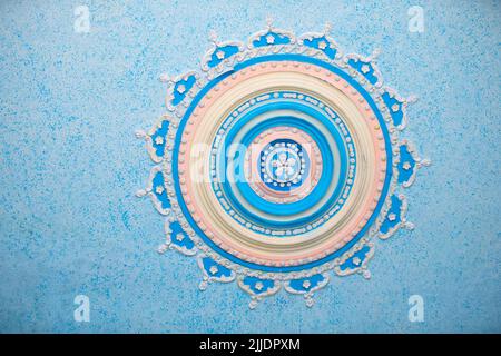 Round beautiful stucco pattern on the ceiling. Relief plaster, relief pattern blue background. Part of an old ceiling decorated with a clay pattern. Stock Photo