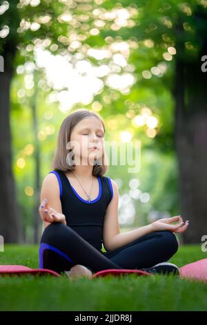 meditation in the park in the lotus position little girl meditates and relaxes Stock Photo