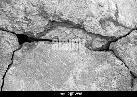 Big deep winding crack on old plastered wall. Remains of plaster. Numerous layers of paint. Black and white photo. Copy space. Close-up. Selective foc Stock Photo