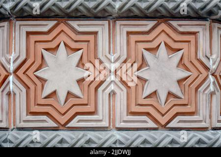 A fragment of a wall trimmed with carved multi-colored tiles with eight-pointed stars. Close-up. Selective focus. Stock Photo