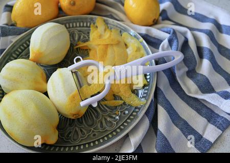 Lemon fruits and peeled strips for zest or making limoncello. Peeler, lemons and zest. Copy space, selected focus. Stock Photo