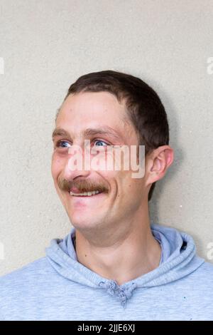 Portrait of young delighted, crazy man isolated on gray background. Face expressions and gesticulation Stock Photo