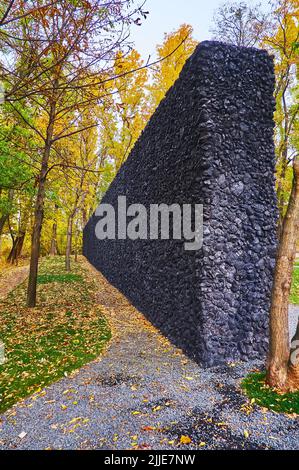 KYIV, UKRAINE - OCT 17, 2021: The black Crystal Wailing Wall in Babyn Yar (Babi Yar) Holocaust Memorial Park, surrounded with yellow autumn trees, on Stock Photo