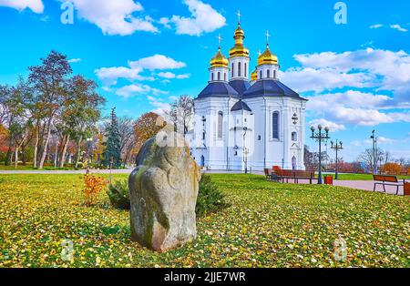 The scenic autumn park with green lawn, dry yellow fallen leaves and a view of historic St Catherine's Church, Chernihiv, Ukraine Stock Photo