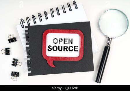 Business concept. There is a magnifying glass, a notebook and a sign on the table - OPEN SOURCE Stock Photo