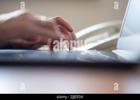 Low angle view of female hands typing on laptop computer. Blurred motion of the fingers. Stock Photo