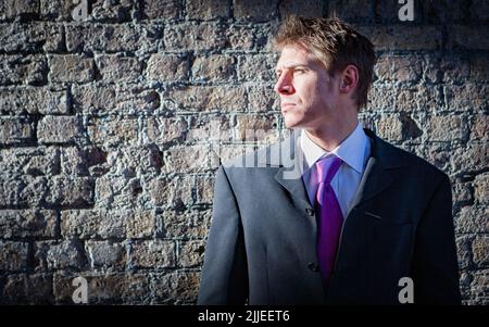 Urban Business; into the light. A handsome young businessman looking forward toward a bright future; candid waist-up portrait on location. Stock Photo