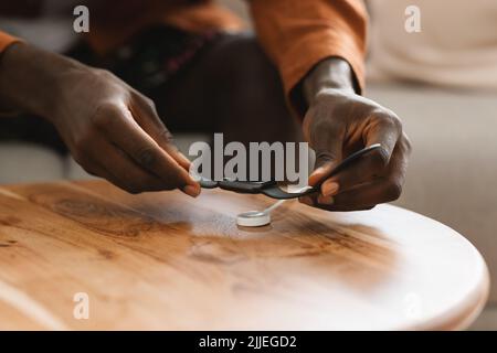 Modern gadgets. Black man putting new smartwatch for charging on wireless charger on wooden table, closeup Stock Photo