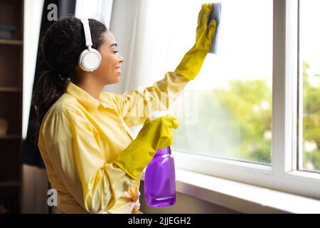 African American Woman Cleaning Window Glass Using Detergent Spray Indoor Stock Photo