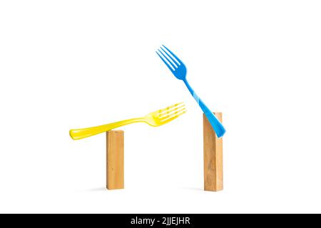 Blue and yellow plastic forks on wooden bricks on a white background with copy space Stock Photo