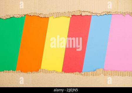 Pieces of ripped cardboard on a multicolor background with copy space Stock Photo