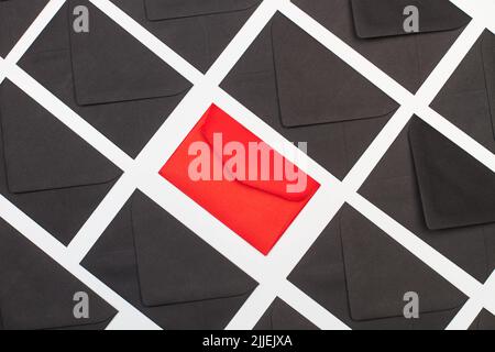 Black envelopes and one red on a white background in a top view Stock Photo