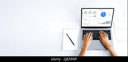 Panoramic photo of laptop with financial charts at screen, mockup for announcement, advertising. Top view, female hands lie on a laptop keyboard with a graphs at white screen, typing text. Copy-space Stock Photo