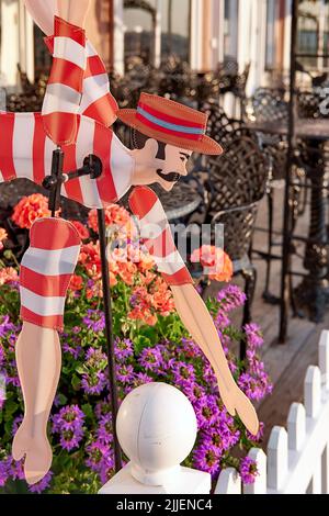 A vibrant whirligig of a male Victorian-era swimmer adds charm and color to a seaside-themed garden and patio. Stock Photo