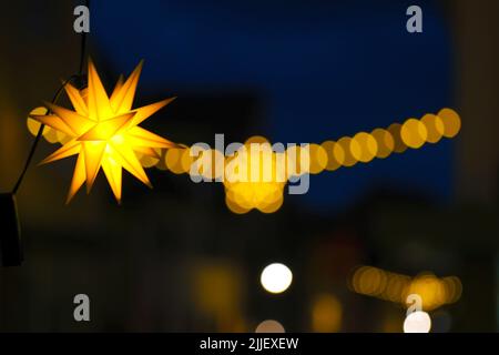 christmas lantern.glowing garlands and lanterns on branches against a blue sky.Night festive illumination. Dark background with garlands. Stock Photo