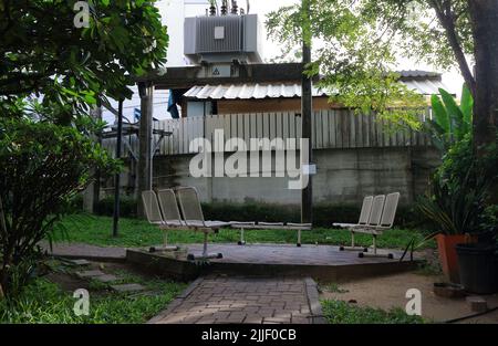 Rows of chairs in smoking area near transformer in the garden Stock Photo