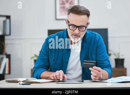 Planning out my financial goals. a senior businessman using his digital tablet to make online card payments. Stock Photo