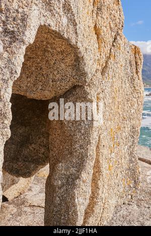 Closeup of a crevice or gully formed by the erosion of sea water. Large boulder or sandstone on a beach with the ocean in the background. Sedimentary Stock Photo