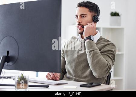 Focused on finding a solution. a handsome young male call center agent working in his office. Stock Photo